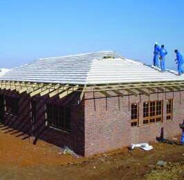 Roof trusses being installed on brick house